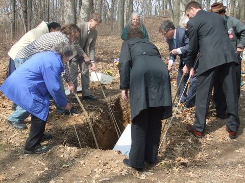Group of people lowering remains into grave